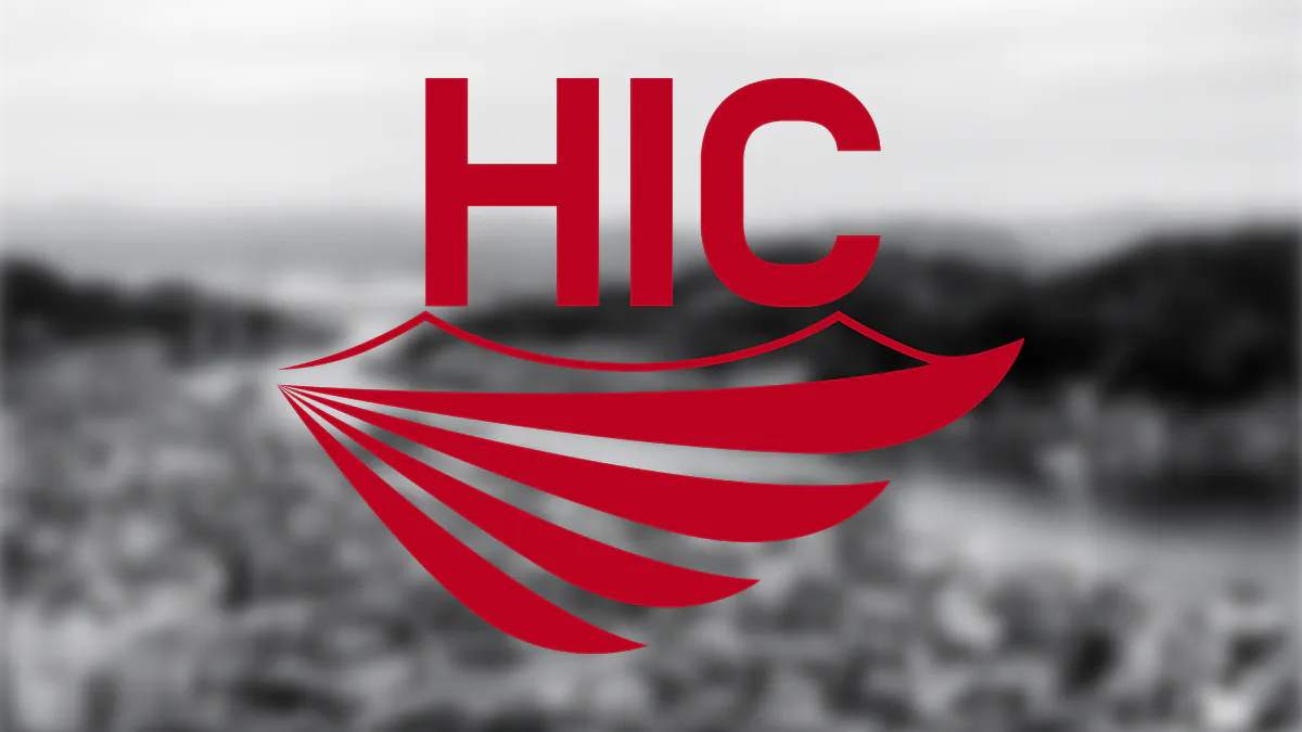 The HIC logo, in red, overlaid on a blurry black and white image of Onomichi in Hiroshima