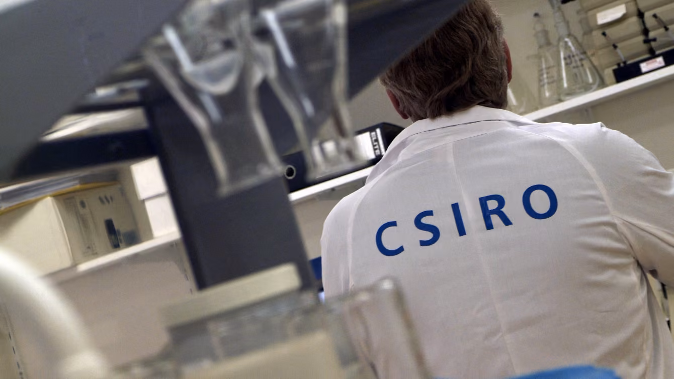 scientist in a lab wearing a coat with CSIRO on the back
